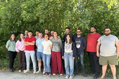 Groupe d'environ quinze participants au projet, posant ensemble en extérieur après la réunion bilan.