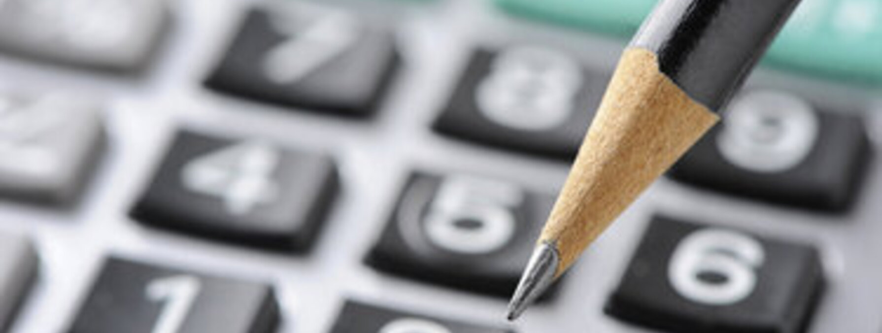 Crayon à mine posé sur le clavier d'une calculatrice en gros plan, évoquant un travail de calcul financier